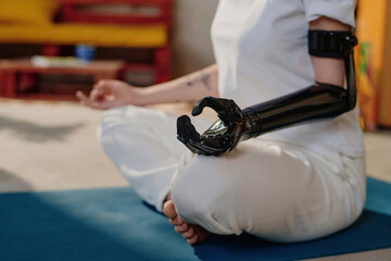Cropped image of young woman meditating in lotus position at home to improve mental health
