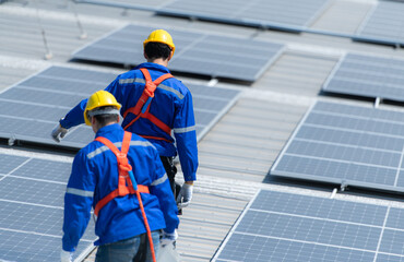 Both of technicians is installing solar panels on the roof of the warehouse to change solar energy...