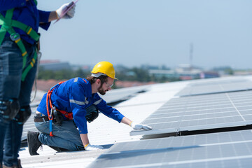 Both of technicians is installing solar panels on the roof of the warehouse to change solar energy into electrical energy for use in factories.