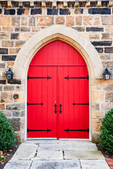 facade design. Close-up view of a wooden red entrance door in a stone wall. with lanterns at the entrance.