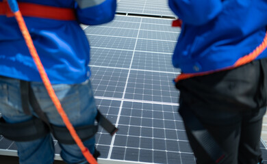 Both of technicians is installing solar panels on the roof of the warehouse to change solar energy into electrical energy for use in factories.