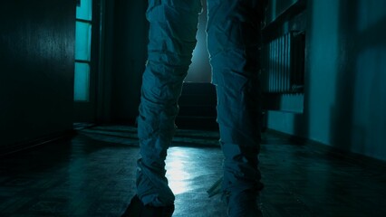 Mummy covered in white cloth ribbons walking in the corridor with blue lightning, feet close up.