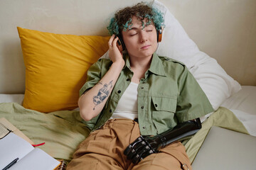 Portrait of stylish teenage girl with curly hair listening to good music in headphones