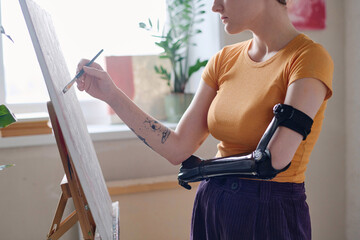Cropped image of girl with prosthetic arm learning painting