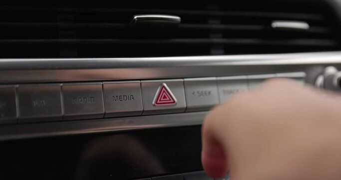 Man pressing hazard button on car while driving - close up