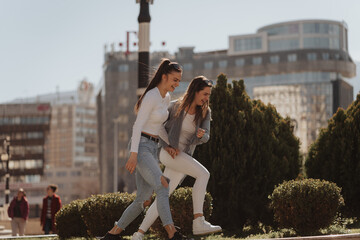 Two girls walking down a sidewalk in a city