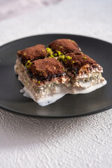 Cold baklava with cocoa on a black plate