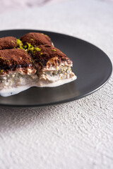 Cold baklava with cocoa on a black plate
