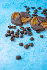 coffee beans and dried orange chocolates on blue background