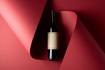 Bottle of red wine with old empty label on a red background.
