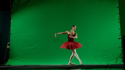 Woman on chroma key background of green screen. Beautiful ballerina in red tutu and pointe shoes...