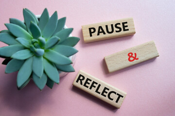Pause and Reflect symbol. Concept words Pause and Reflect on wooden blocks. Beautiful pink...