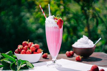 Still life - amazing strawberry milkshake cocktail with straw on nature backdrop