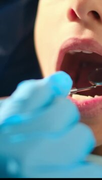While assessing a young patient for tooth decay, a compassionate female dentist employs a dental probe and angled mirror.