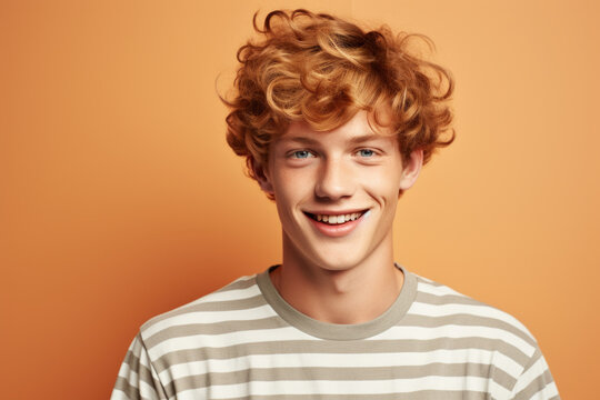 Young man with curly red hair is captured smiling at camera. This image can be used to portray happiness, positivity, or friendly demeanor. It is suitable for various projects and designs.