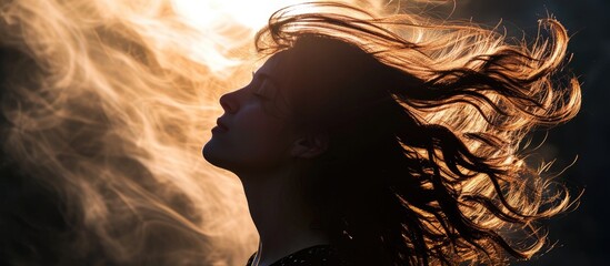 Backlit silhouette of woman's hair in motion. - obrazy, fototapety, plakaty