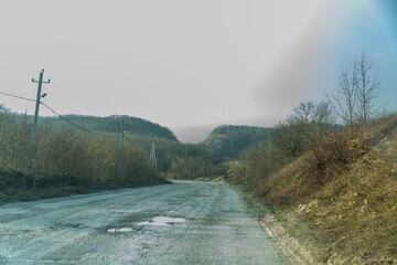wide country dirt rocky road with puddles after rain to a mountain pass in the form of a saddle...