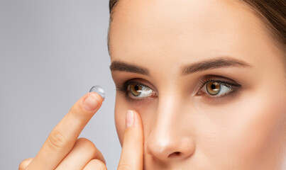 Beautiful young woman holding a contact lens on her finger. Eye care and choice of means to improve...
