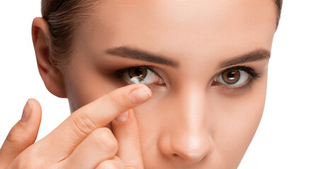 Beautiful young woman holding a contact lens on her finger. Eye care and choice of means to improve...