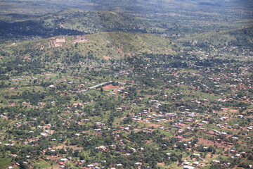 View from helicopter overflies African villages made of mud in traditional style (tukul houses) surrounded by tick green jungle