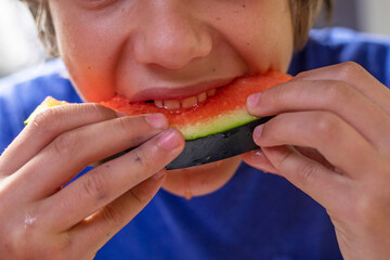 boy eats a piece of red watermelon with both hands. Watermelon Day