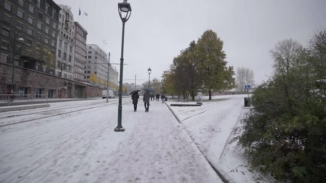 people walking with umbrelas on snowy roads in oslo in slow motion