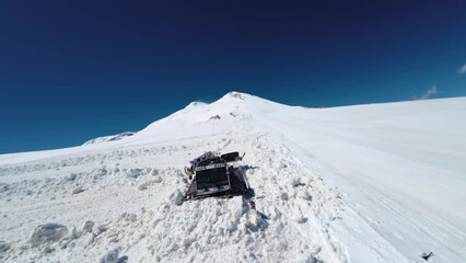 snowcat rides on a snowy parking lot at a winter ski resort in the mountains. Aerial top view from drone, clearing snow on winter slope of mountain resort