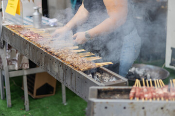 Focus selection: Pork grilled vendors, street food available in Thailand. Hand of a hawker grilled...