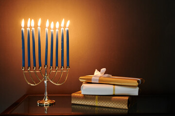 Stack of packed giftboxes and menorah with nine burning candles prepared for celebration of Hanukkah standing in front of camera