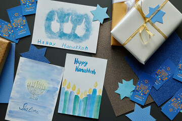 Above angle of variety of handmade postcards and symbols of Hanukkah lying on table next to stack...