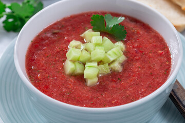 Gazpacho soup garnished with cucumber and cilantro, in bowl, horizontal
