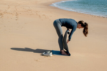 Young sporty woman doing push-ups on the beach at morning