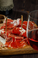 Slices of jamon serrano, jamon iberico, smoked sausage, ham or prosciutto crudo parma on wooden board with. Wooden background. Still life. Selected focus.