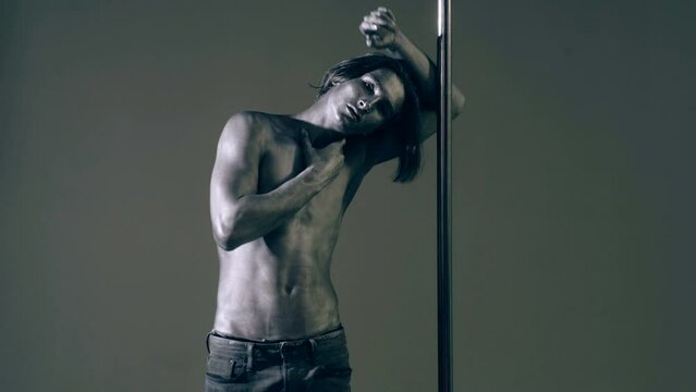Sexy man pole dancer. Guy does gymnastic exercises on pole dance. Pole dancing for slim fitness body. Flexibility. Pole dance. Pylon dancing strength, flexibility, and grace. Strip dancer.