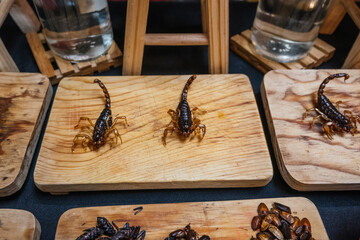 Fried scorpions and insects, traditional pre-Hispanic Mexican food, served on a wooden board.