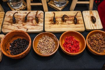 Fried scorpions and insects, traditional pre-Hispanic Mexican food, served on a wooden board.