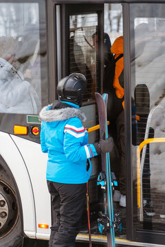 A skier in vibrant gear boards a bus, capturing the ease of access to ski resorts. Ideal for travel, winter sports, and lifestyle content