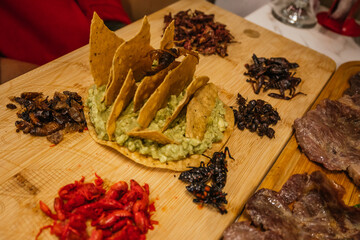 Delicious insect board with guacamole and toast, with grasshoppers, chinicuiles, escamoles,...