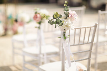 Ceremony in the bosom of nature. White chairs with flowers set in the grass. white chairs lined up...