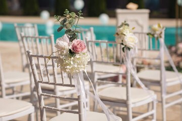 Ceremony in the bosom of nature. White chairs with flowers set in the grass. white chairs lined up for an event accompanied by a bouquet of white flowers.