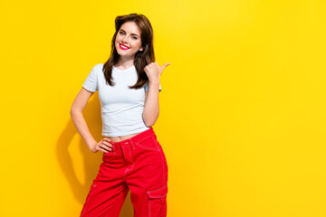 Portrait of satisfied girl with retro hairdo wear white t-shirt indicating at discount empty space isolated on yellow color background