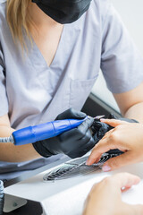 Nail manicure in woman beauty salon. Electric nails file drill in action, finger close up or detail with color background.