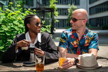 Fashionable mid-age man carrying a colorful hawaiian shirt and actractive young woman of color...