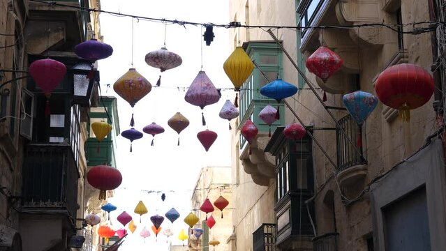 Malta Valetta street decoration - Chinese lanterns are strung over a narrow street between the facades of buildings
