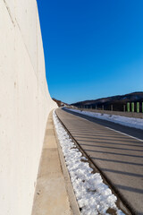 Obraz premium An empty two-lane highway. Winter scene. Empty asphalt road in rural landscape at sunset with blue clouds. Asphalt highway road with beautiful blue sky in pastoral rural environment.
