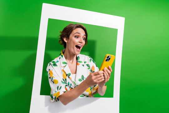 Photo of impressed funky girl dressed print shirt arms typing modern gadget paper frame isolated green color background