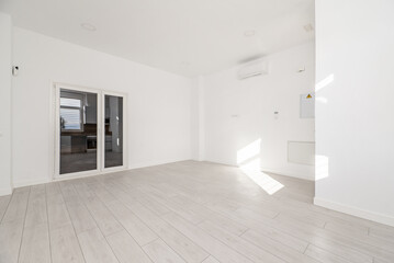 Obraz premium An empty room in an apartment with white walls, light wooden floors, air conditioning high on the wall and double white aluminum