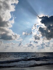 a cloudy blue sky with a sunbeam plays above water