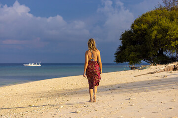 A young woman is walking on a sand beach in Gili Meno, Indonesia
