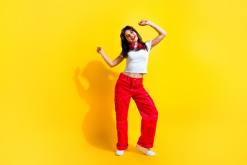 Fototapeta na wymiar Full length photo of cheerful cute woman dressed white t-shirt headphones dancing discotheque empty space isolated yellow color background